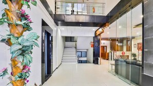 Un moderno vestíbulo de hotel con una escalera, una recepción y una división de vidrio.