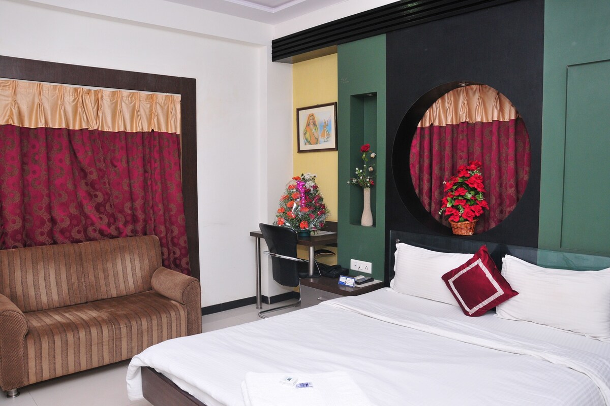 A hotel room with a bed, a sofa, a desk, and a chair.
