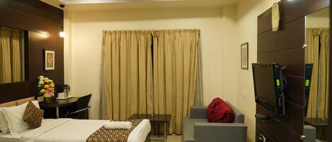 Una camera d'albergo con due letti, una scrivania, un divano, una televisione e uno specchio.