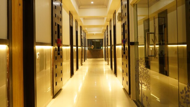 Un pasillo largo y bien iluminado con puertas a ambos lados, que conduce a habitaciones.