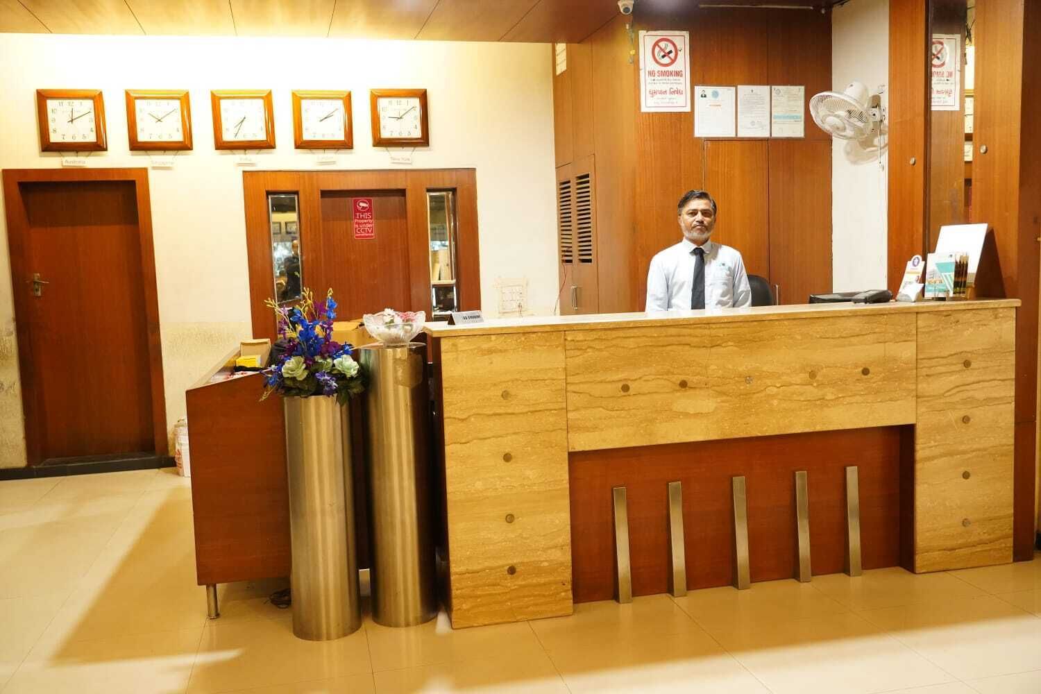 A reception desk with clocks, a no-smoking sign, and a fan.