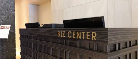 Un mostrador de recepción con el rótulo 'BIZ CENTER', diseño moderno, superficie plana y una pequeña zona de exhibición.