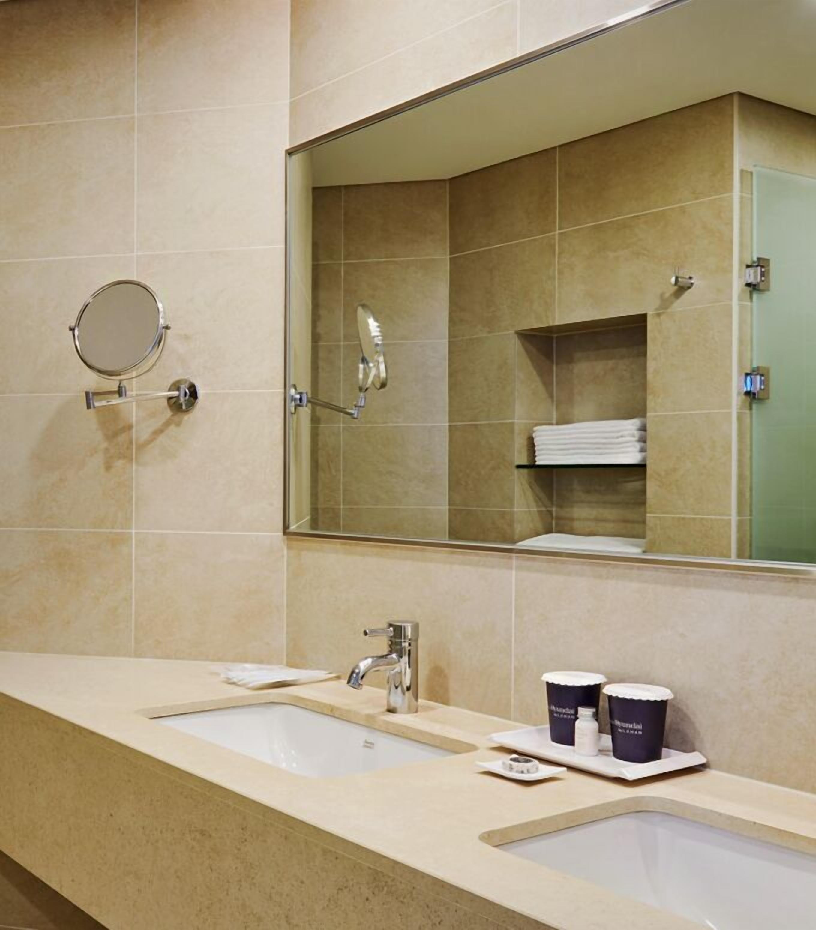 A bathroom with two sinks, a large mirror, and a towel rack.