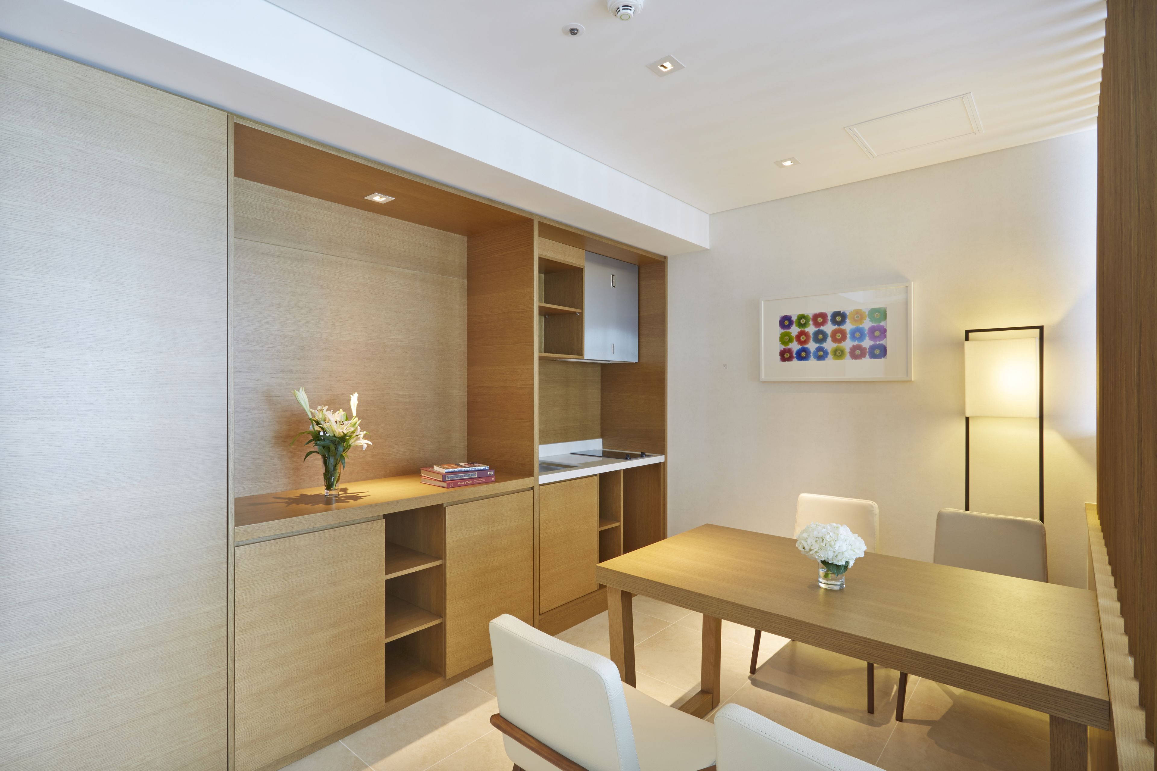 A modern kitchen with wooden cabinets, a dining table, and chairs.