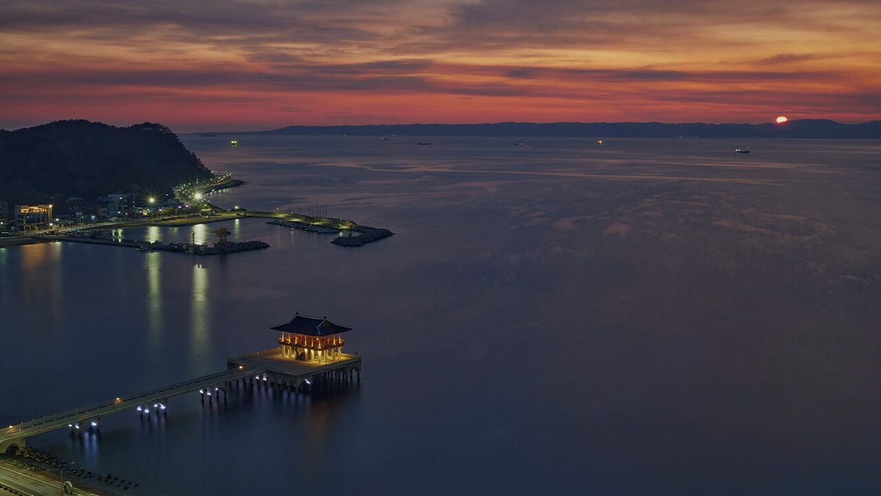 A waterfront property with a pier, a dock, and a building with a pagoda-style roof.