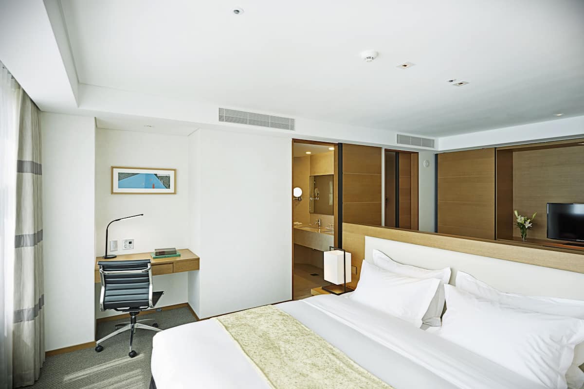 A hotel room with a bed, desk, chair, and a television.