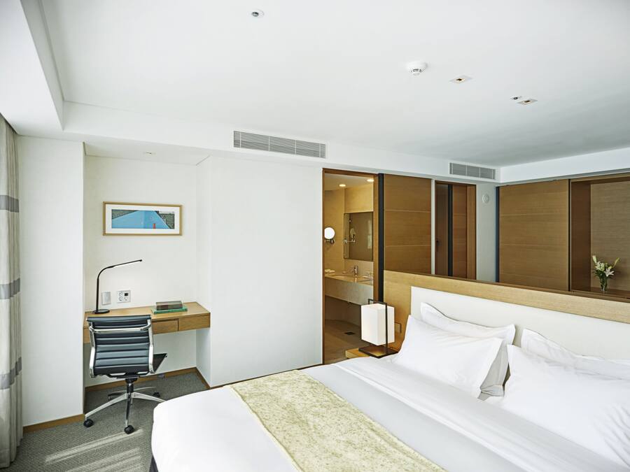 Habitación de hotel con cama, escritorio, silla y televisor.