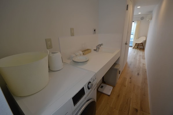 A modern bathroom with a large sink, a washing machine, and a compact toilet.