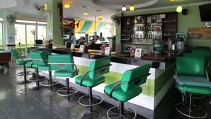 A restaurant with green bar stools, a counter, and a variety of hanging lights. - Ponderosa Resort (Pattaya)