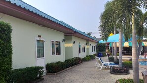 A hotel with a paved walkway, outdoor seating, and a pool area. - Ponderosa Resort (Pattaya)