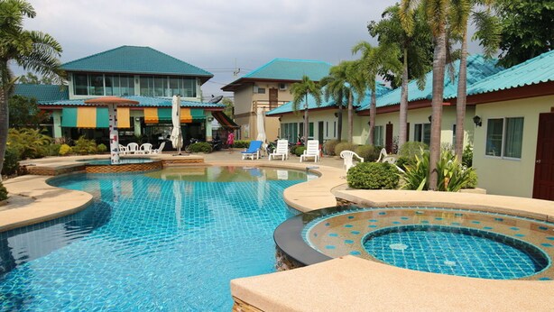 A swimming pool with lounge chairs and a building with a blue roof. - Ponderosa Resort (Pattaya)