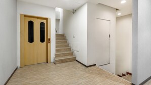 Un pasillo con suelo de madera, una puerta de madera y una escalera que sube a otro piso.