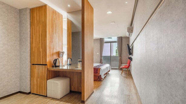 Habitación de hotel moderna con escritorio de madera, cama, un pequeño espacio de descanso y vistas al exterior.