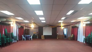 A large room with a high ceiling, multiple tables, chairs, and a stage area. - Persatuan Kebajikan Sri Sakthi Ashram - Hostel (Tangkak)