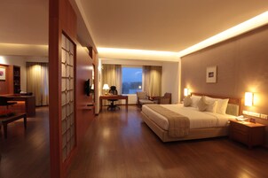 Habitación de hotel con una cama grande, un escritorio con silla, una mesita y un televisor.