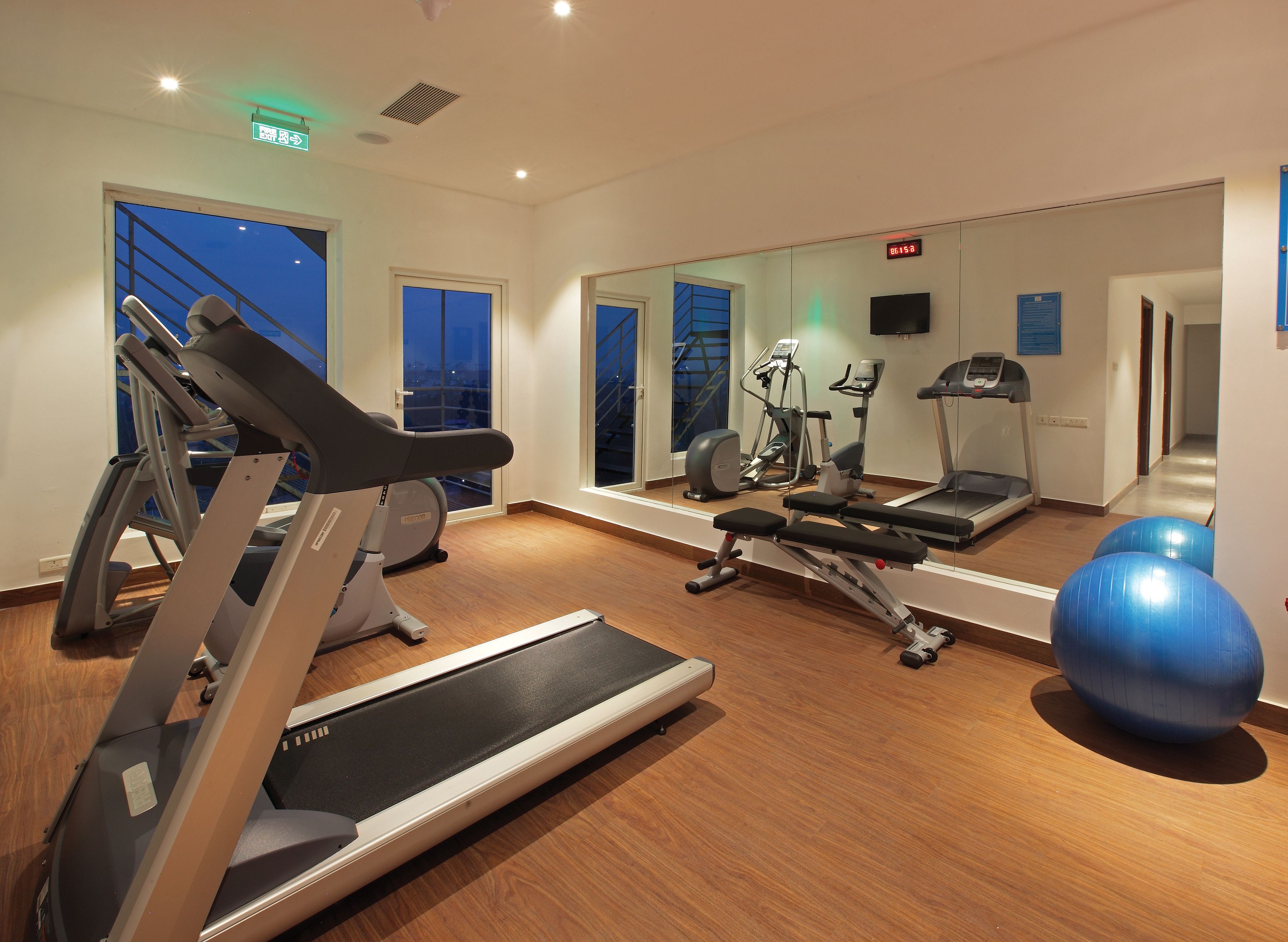 A gym with treadmills, exercise balls, and a mirrored wall.
