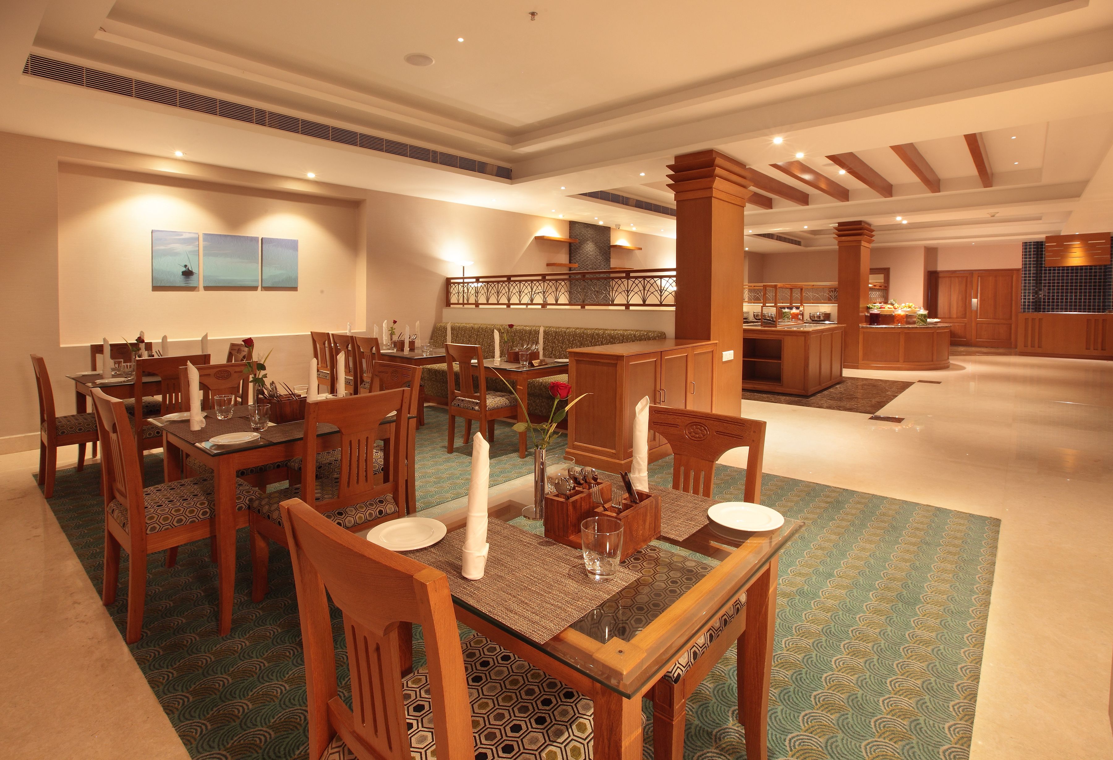 A spacious dining area with multiple wooden tables and chairs, a central island, and a view of the kitchen area.
