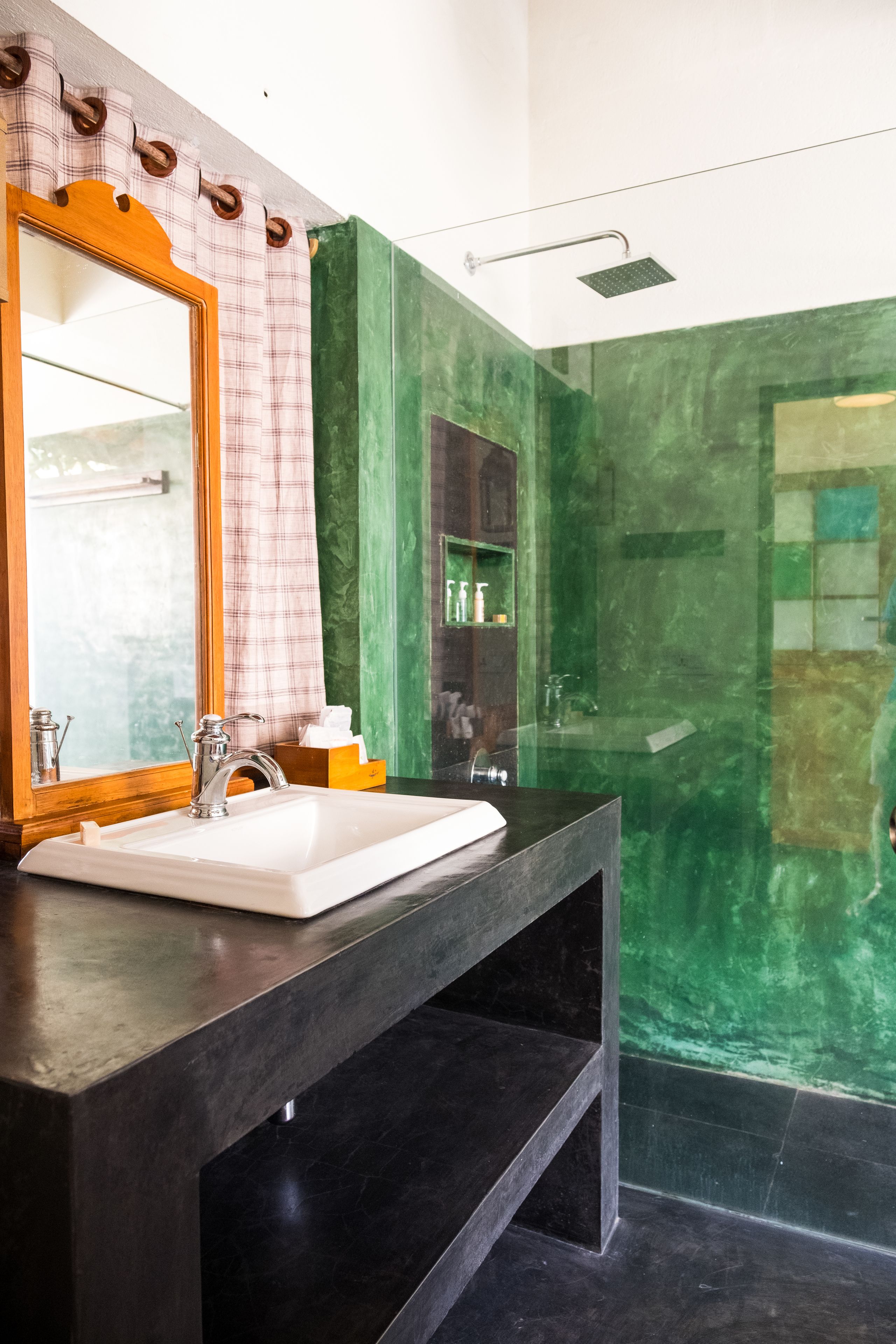 A bathroom with a large mirror, a white sink, and a shower area.