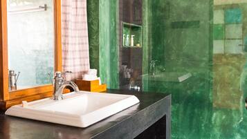 A bathroom with a large mirror, a white sink, and a shower area.