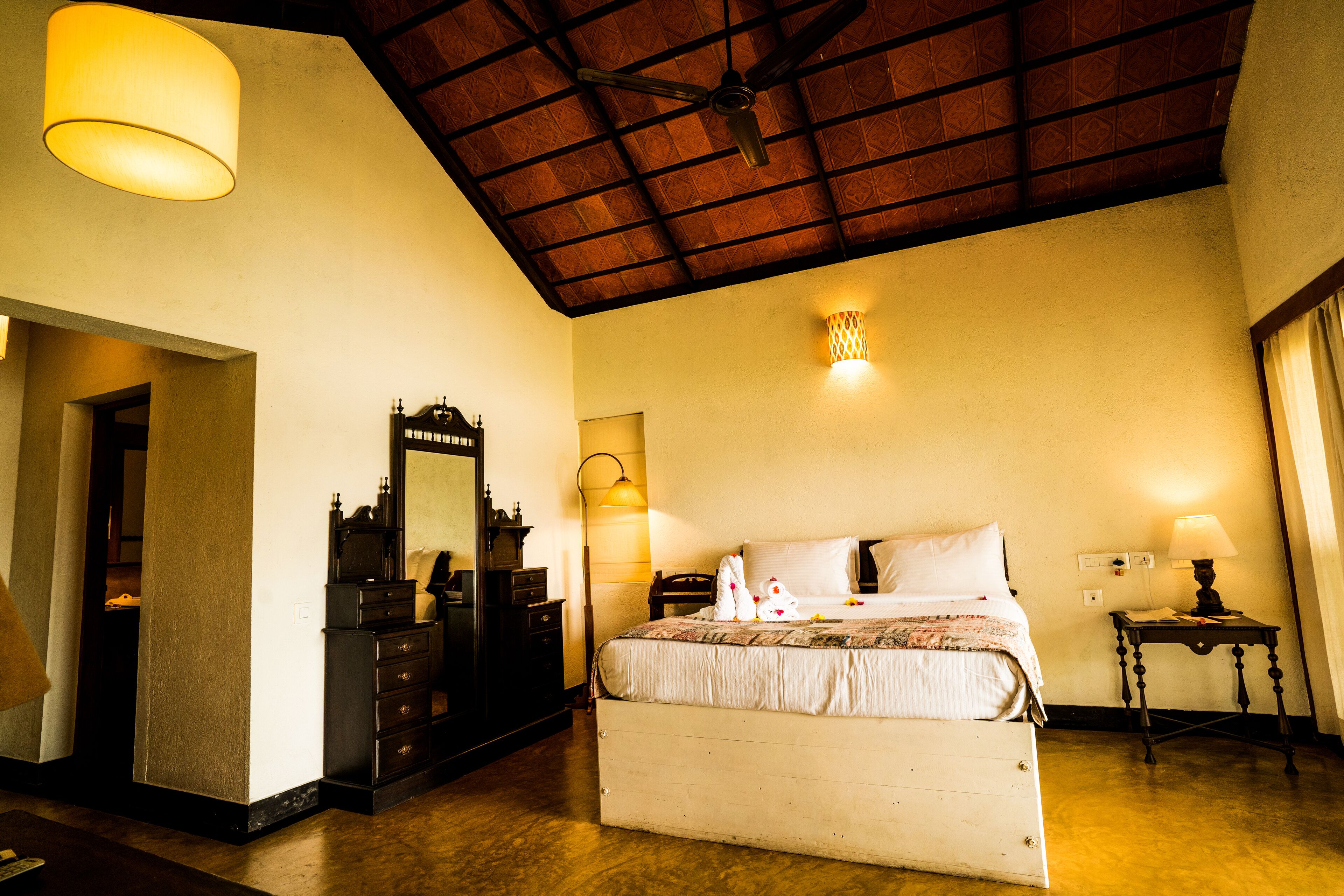 Una habitación de hotel con cama, cómoda, espejo y dos lámparas de pared.