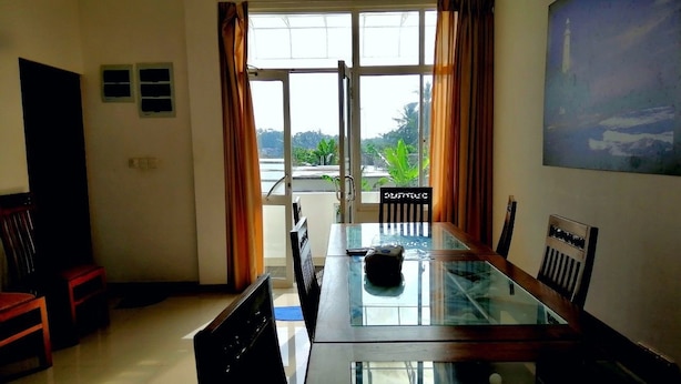 Un área de comedor con una mesa de vidrio, sillas y vistas amplias a través de grandes ventanales.