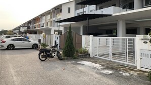 A residential building with a gated entrance, a parked motorcycle, and a white car.
