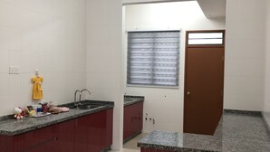 A kitchen with granite countertops, red cabinets, and a window with blinds.