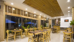 Un amplio comedor con mesas y sillas de madera, ventanas grandes y un techo con diseño geométrico.