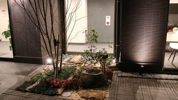 A well-maintained outdoor garden area with a variety of plants and a central fire pit. - Floral Hotel · SakaisuJi-Honmachi Osaka (Osaka)