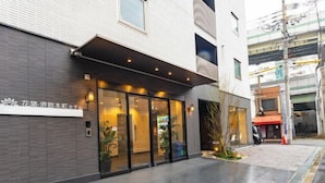 A modern building with a glass entrance, a signboard, and a paved walkway. - Floral Hotel · SakaisuJi-Honmachi Osaka (Osaka)