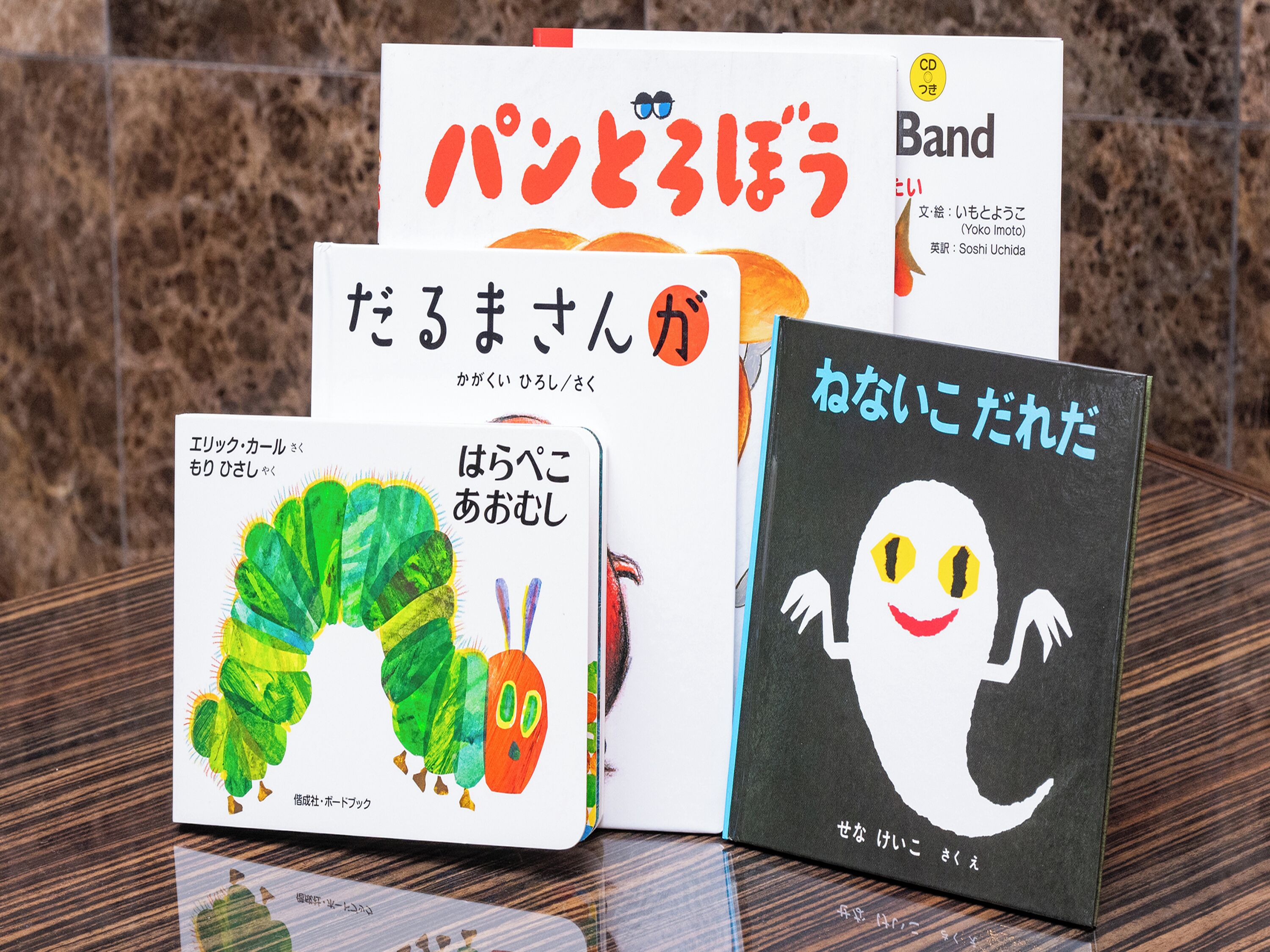 A collection of books with Japanese text, placed on a wooden surface.