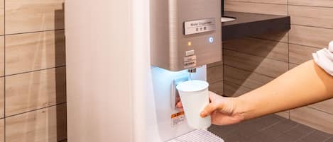 Un dispensador de agua con portavasos, pantalla digital y etiqueta de advertencia.