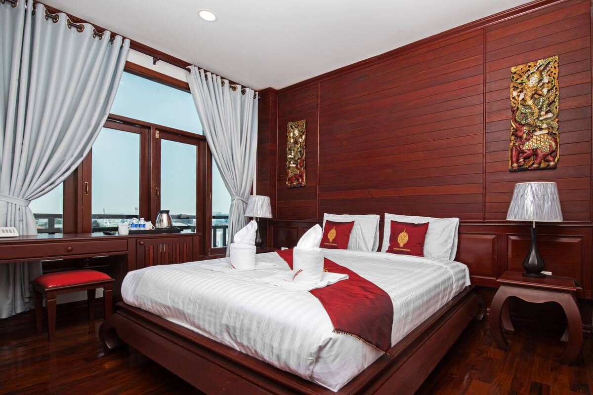 A hotel room with a large bed, a desk, and a view of the city.