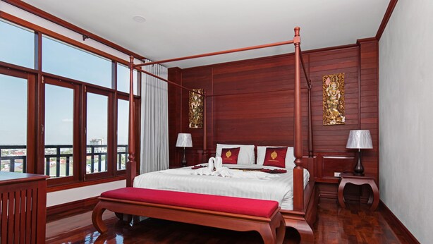 A spacious bedroom with a large bed, wooden floor, and a balcony view. - Manorom Chateau Hotel (Vientiane)