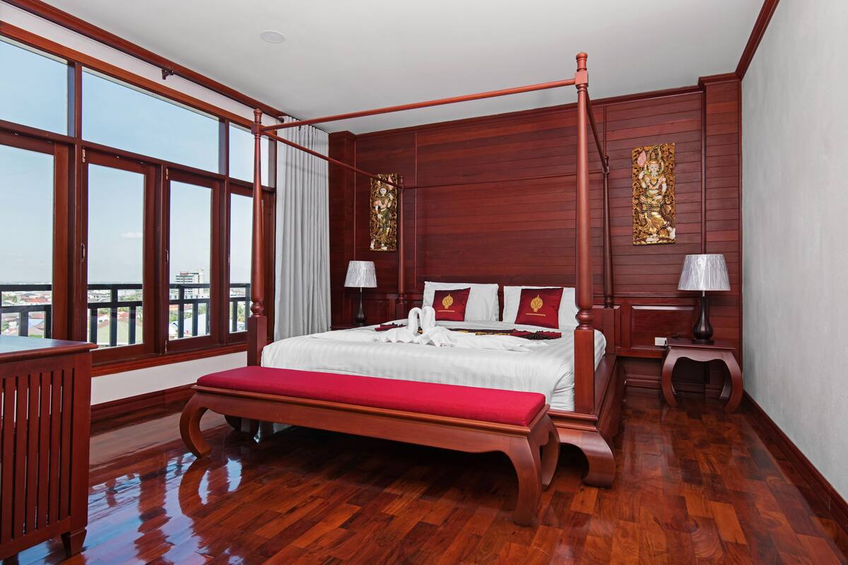 A spacious bedroom with a large bed, wooden floor, and a balcony view.