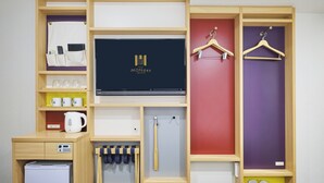 A hotel room with a TV, a mini-fridge, a coffee maker, a shoe rack, and a wardrobe with a mirror. - hotel MONday Tokyo Nishikasai (Tokyo)