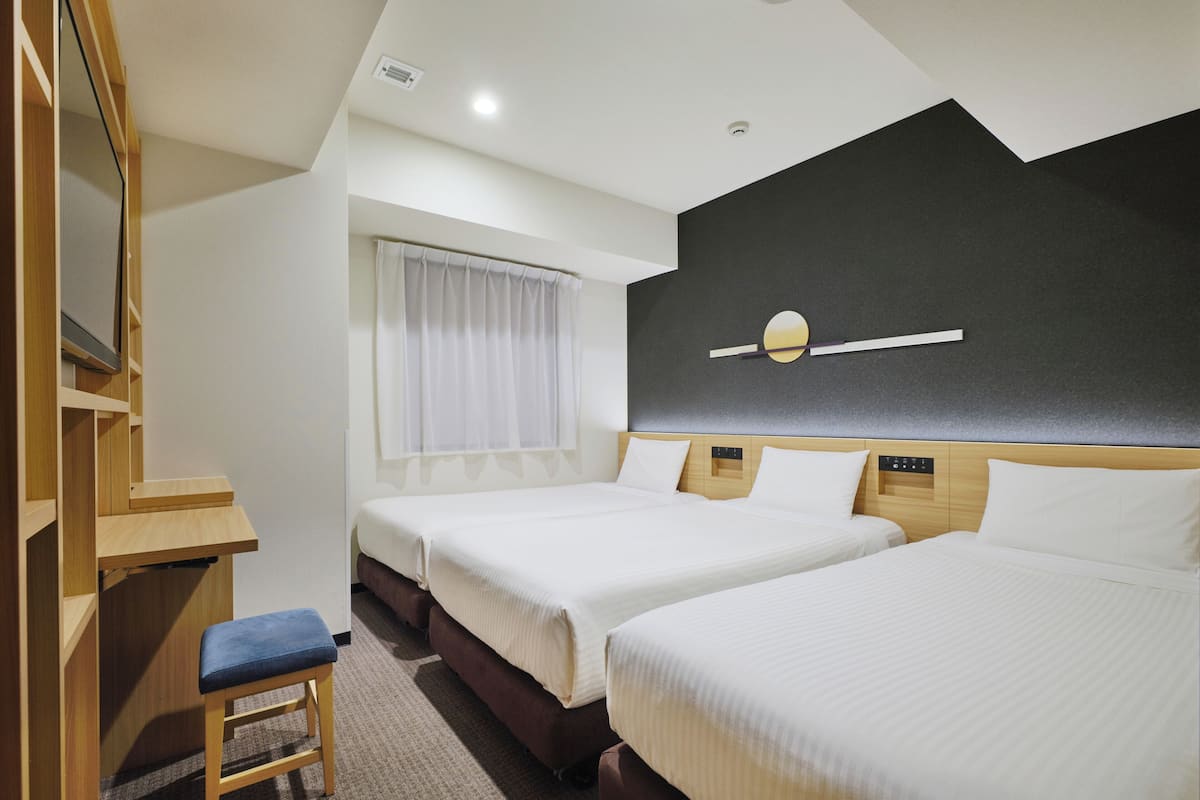 Habitación de hotel con dos camas, un escritorio, una silla y un espejo grande.