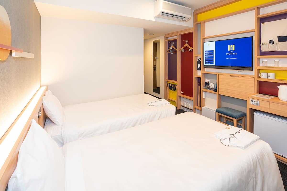 Habitación de hotel con dos camas, televisión, escritorio y armario.