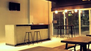 A modern kitchen with a bar area, stools, and a dining table. - The Lively Hotel Kualanamu Airport Medan (Medan)