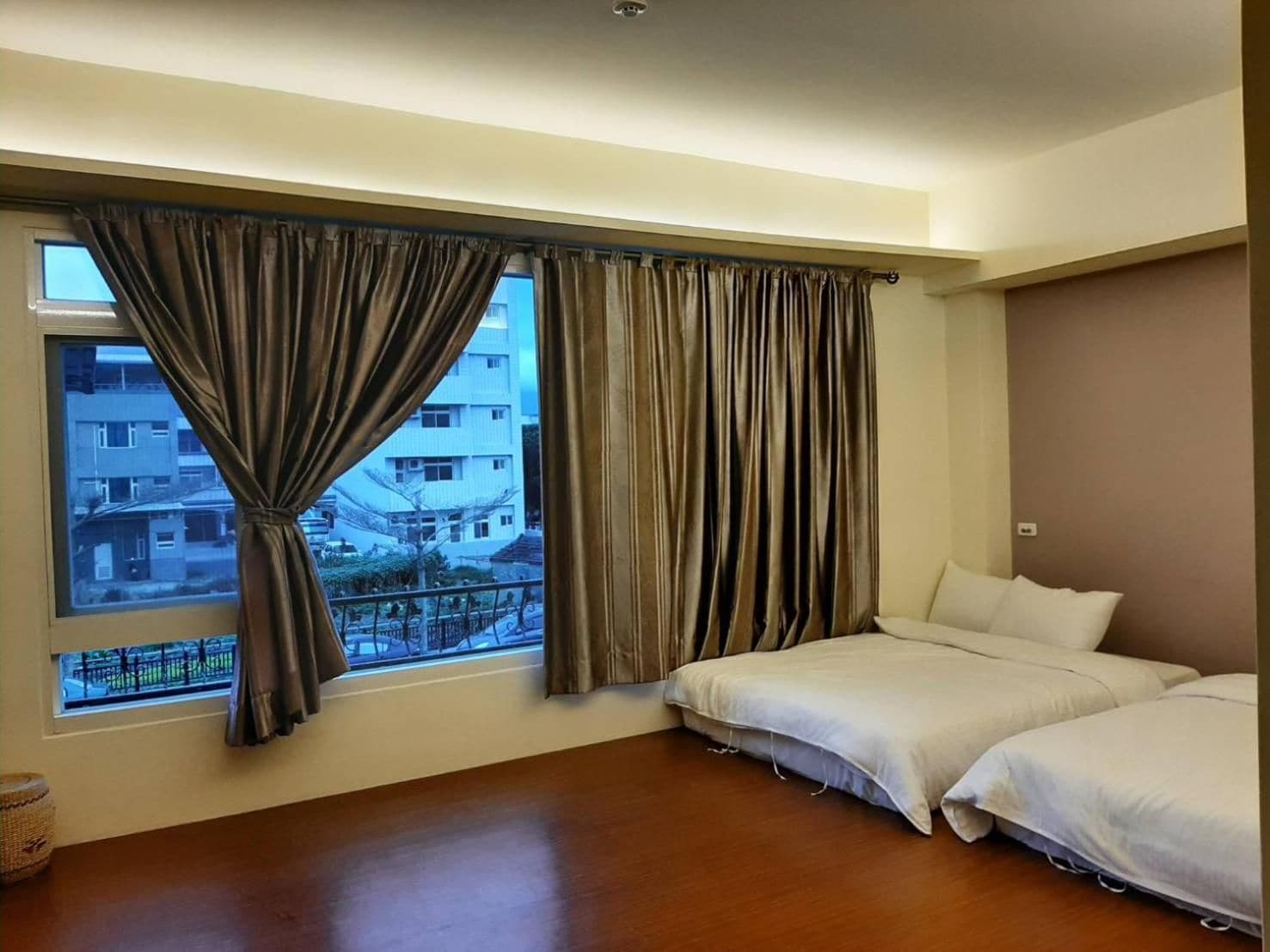 A hotel room with a large window, two beds, and a wooden floor.