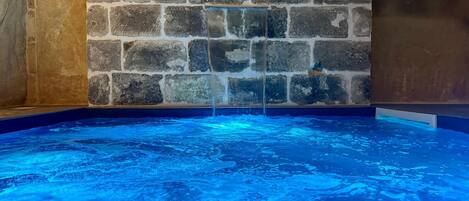 Tinaja con pared de piedra al fondo y superficie de agua azul cristalina.