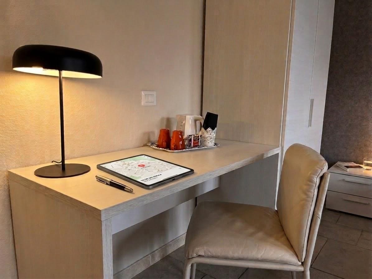 Un escritorio moderno con una lámpara, una tableta y una silla en una habitación de hotel.