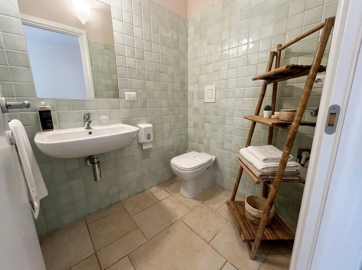 Un bagno con lavandino, WC e uno scaffale di legno con asciugamani.