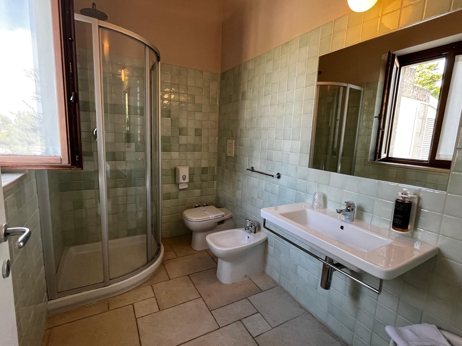 Un baño con cabina de ducha de vidrio, inodoro y lavabo con espejo.