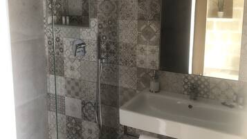 A bathroom with a shower, a sink, and a mirror.