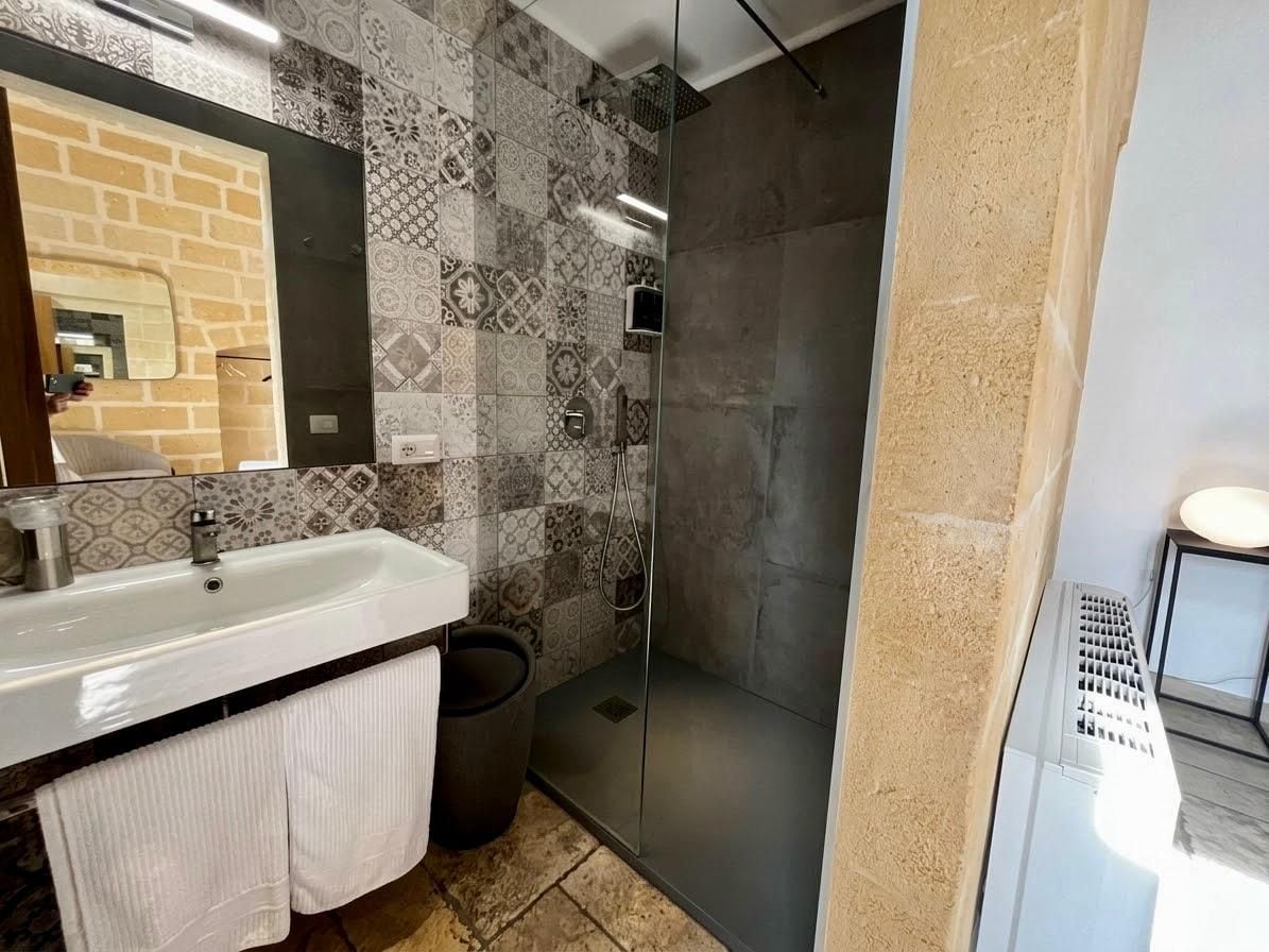 Une salle de bain avec un lavabo, un miroir, une douche et des murs carrelés.