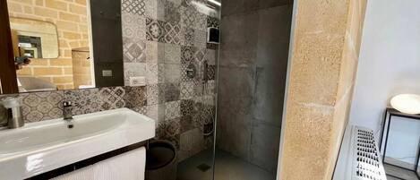 Une salle de bain avec un lavabo, un miroir, une douche et des murs carrelés.