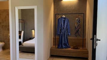 A hotel room with a wooden bench, a robe, and a hat on the bench.