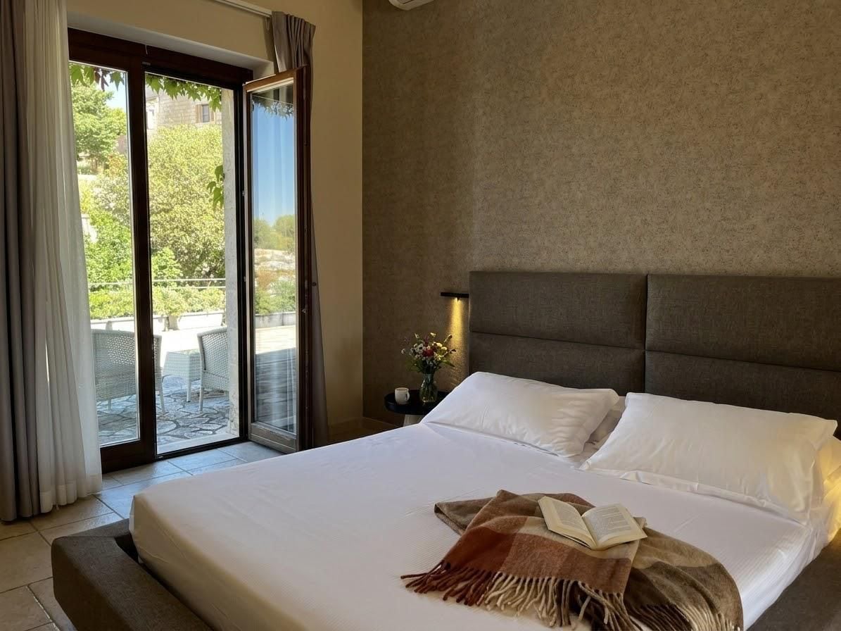 Une chambre d’hôtel avec un lit, une table de chevet, une fenêtre avec des rideaux et une vue sur l’extérieur.
