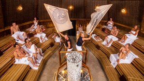 A sauna with wooden benches arranged in a circular pattern around a central fire pit. - Gästehaus Zehmerhof (Walpertskirchen)